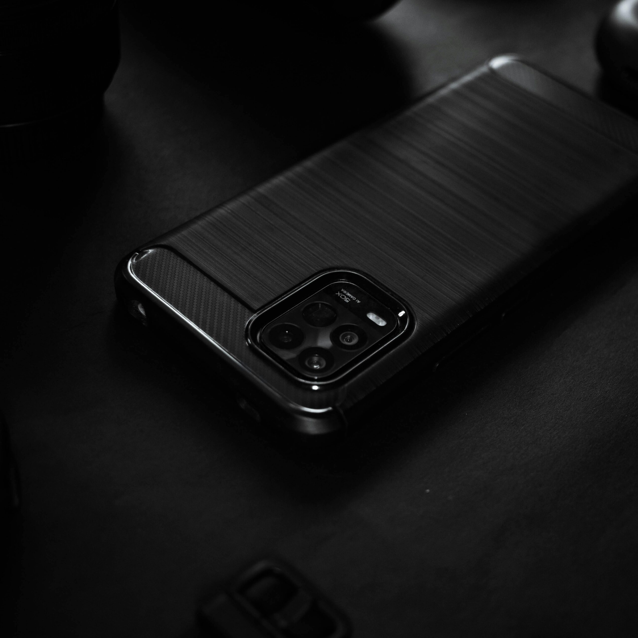 Close-up of a sleek black smartphone on a dark surface, highlighting elegant design.